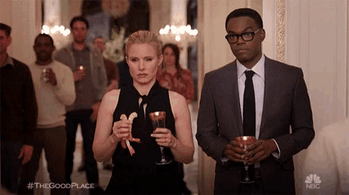 a man in a suit and tie stands next to a woman in a black dress who is holding a glass of wine ..