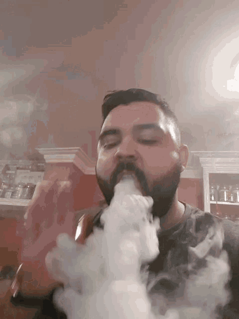 a man with a beard is smoking a hookah in a kitchen