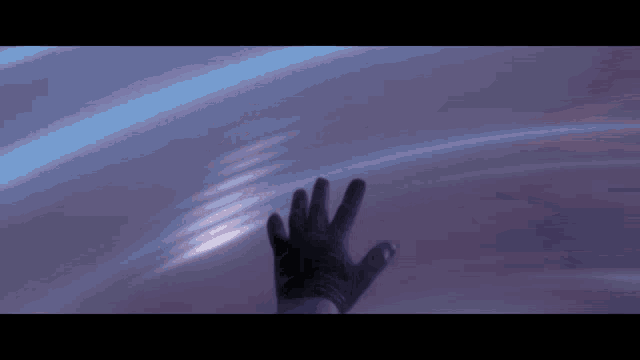 a hand in a black glove is reaching out towards a blue light