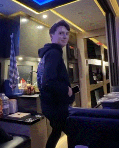 a young man in a black hoodie is standing in a kitchen