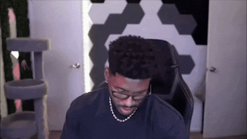 a man wearing glasses and a chain is sitting in a chair .