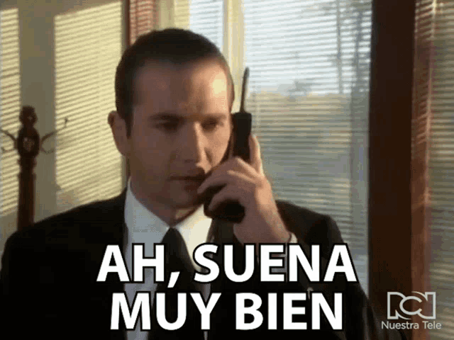a man in a suit and tie is talking on a cell phone with the words ah suena muy bien below him