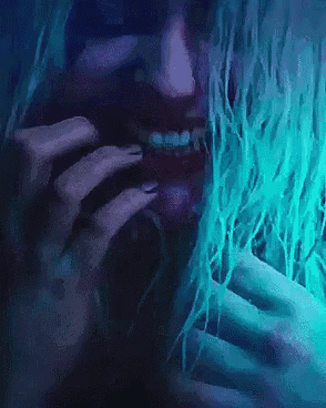 a close up of a woman 's face with a blue light behind her