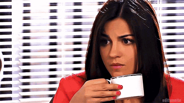 a woman with red nails is drinking from a white cup with editsmaite written on the bottom