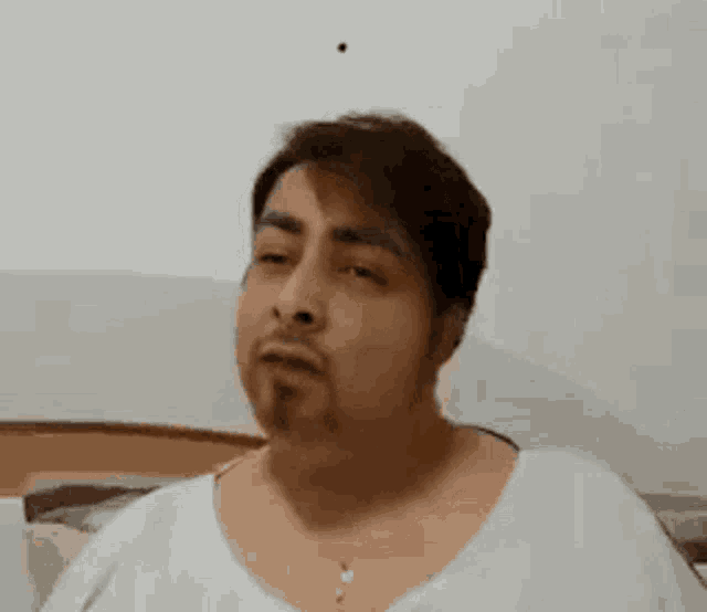 a man with a beard and a white shirt is making a funny face