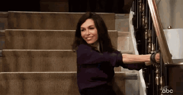 a woman is standing on a set of stairs and smiling .