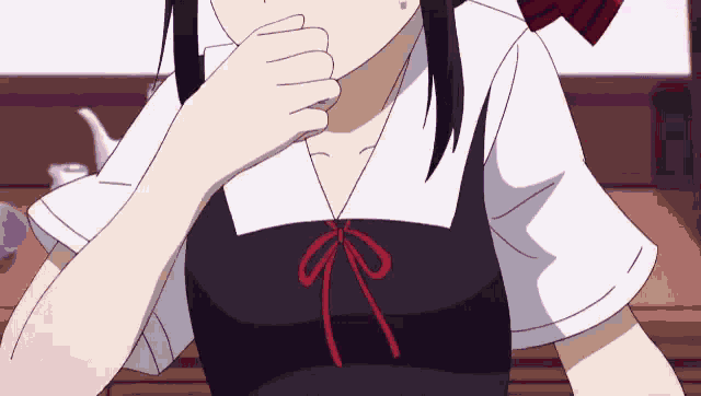 a girl in a black and white dress with a red bow on her neck is sitting at a table .