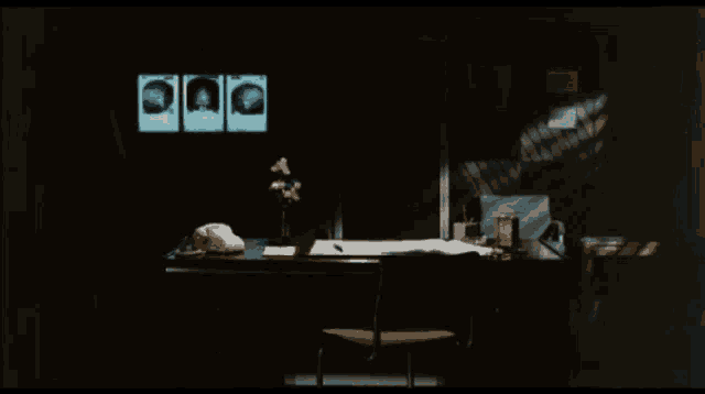 a desk in a dark room with a telephone and a monitor with three pictures of a person on it