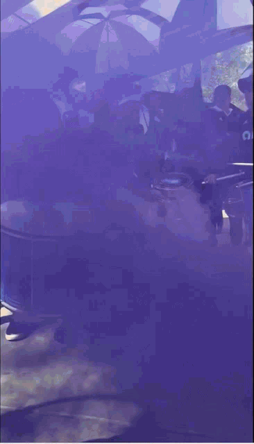 purple smoke is coming out of a drum in front of people