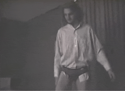 a man in a white shirt and black underwear is standing in front of a curtain