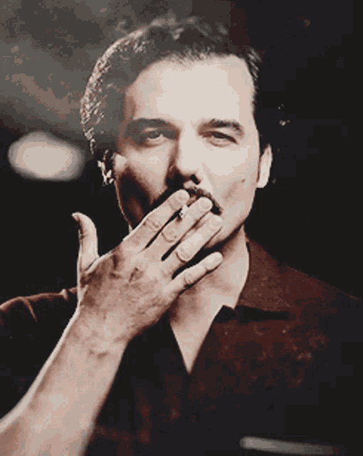 a man is smoking a cigarette with his hand on his mouth