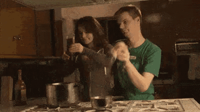 a man and a woman are dancing in a kitchen while preparing food .