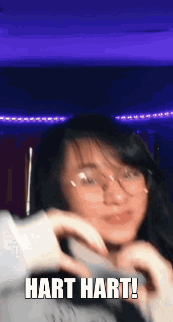 a girl wearing glasses is making a heart shape with her hands and the words hart hart !