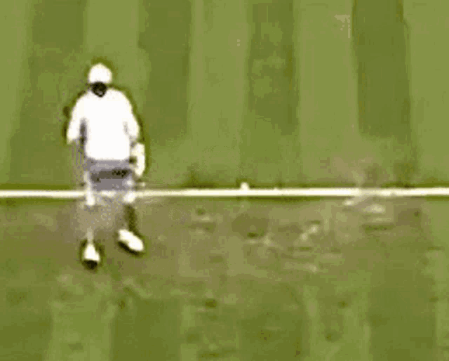 a man is playing tennis on a green field