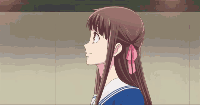 a girl with a pink bow in her hair is wearing a school uniform .