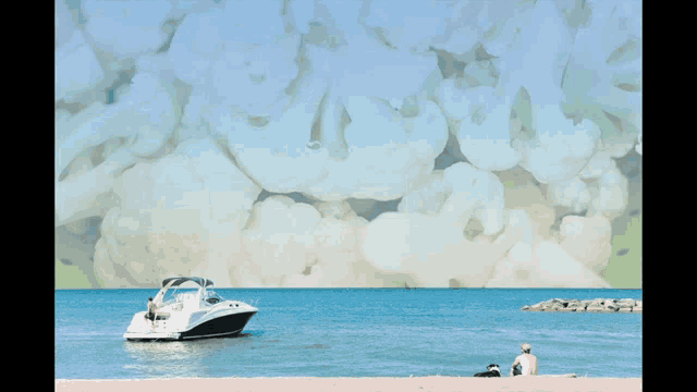 a man sits on the beach looking at a boat in the ocean