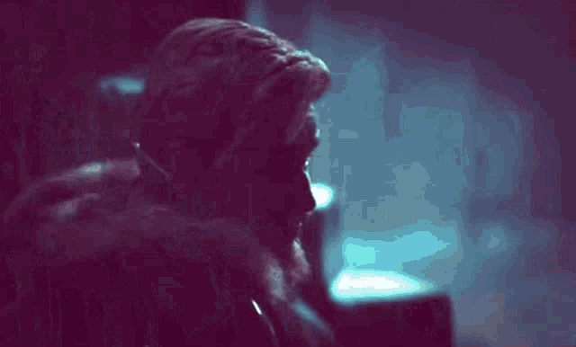 a man is sitting in a chair in a dark room talking on a phone .