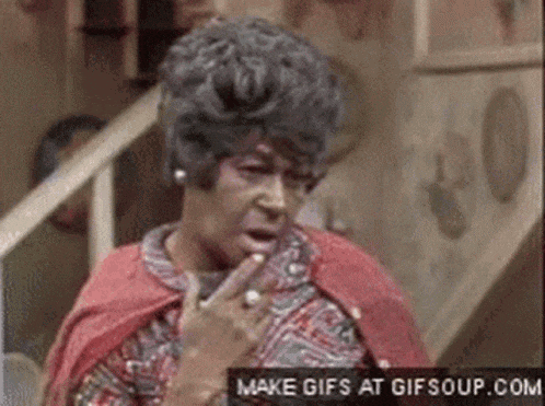 a woman in a red cape is making a funny face while holding her finger to her mouth .