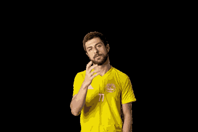 a man wearing a yellow shirt with the number 77 on it