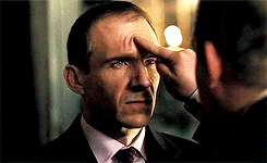 a man in a suit is touching his forehead with his finger