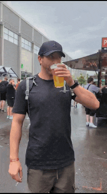 a man in a black shirt is drinking a beer