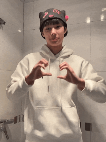 a person wearing a white hoodie and a black hat with gs on it