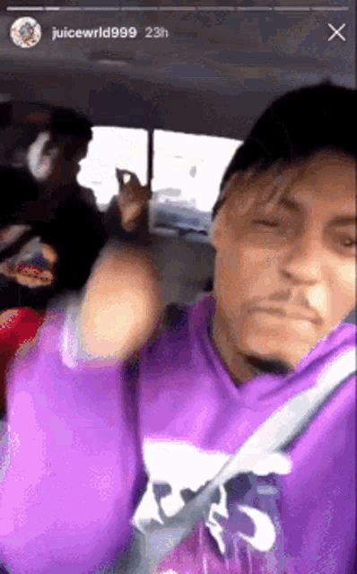 a man in a purple shirt is giving the middle finger