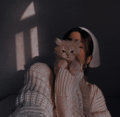 a woman in a white hat is holding a cat in her lap