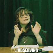 a man in a green shirt with a cross around his neck is sitting at a table