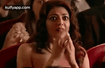 a woman is sitting in a theater looking surprised .