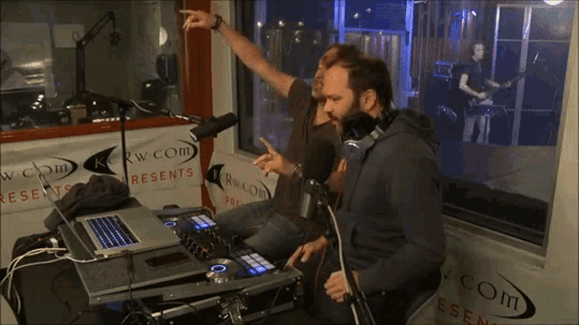 a man is playing a dj set in front of a sign that says kcw com presents