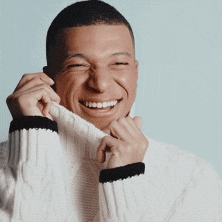 a man wearing a white sweater with black stripes is smiling