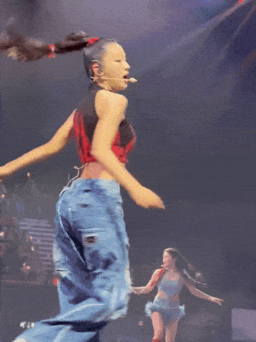 a woman in a red top and blue jeans is dancing