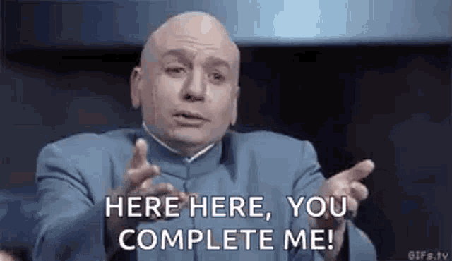 a bald man in a blue suit is making a funny face and says `` here here , you complete me ! ''