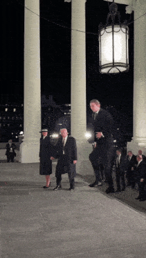 a group of people are walking down a sidewalk in front of the white house