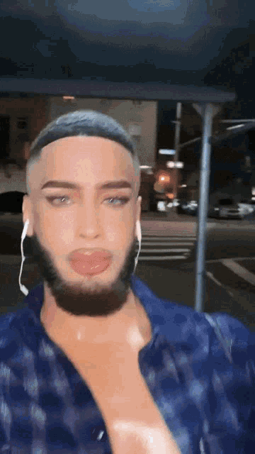 a man with a beard wearing ear buds and a blue shirt