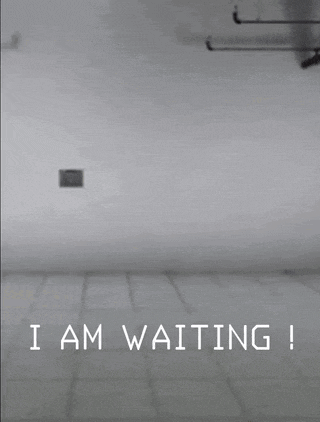 a person in a yellow suit is walking in a room with the words " i am waiting " on the bottom