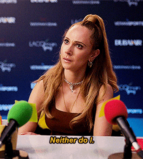 a woman sits at a table with microphones and says neither do i