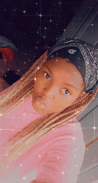 a woman wearing a pink shirt and a black bandana looks at the camera