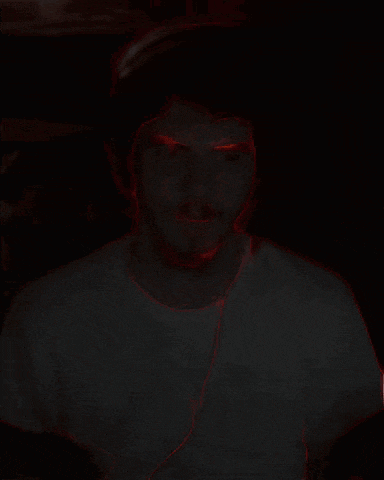 a man 's face is glowing in the dark and has red eyes