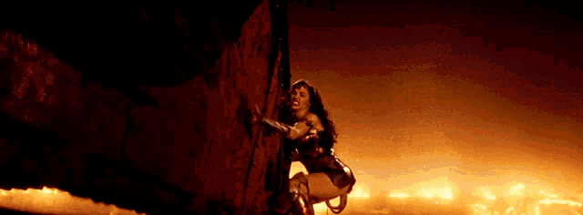 a woman in a wonder woman costume is climbing up a red wall .