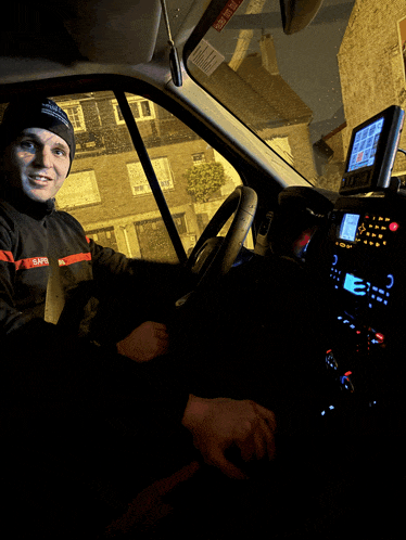a man sitting in a car with a sticker on the windshield that says " emergency exit "