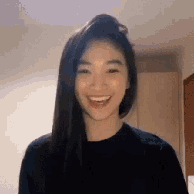 a young woman with long hair is smiling and looking at the camera .