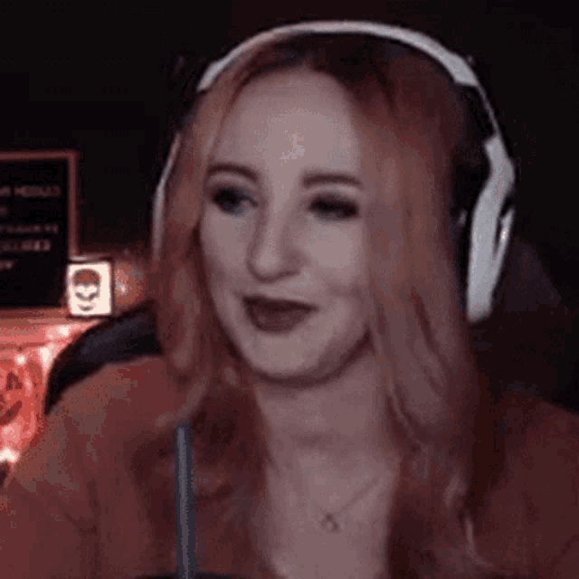 a woman with pink hair is wearing headphones and drinking from a cup .