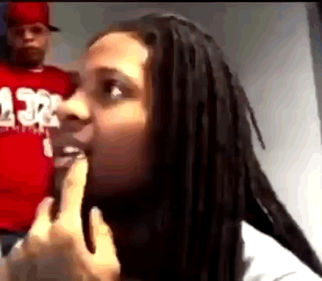a man in a red shirt is standing behind a woman with dreadlocks