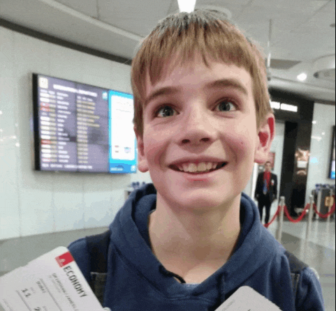 a young boy is smiling while holding an economy ticket