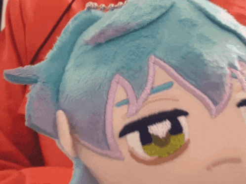 a close up of a stuffed animal with blue hair and purple ears