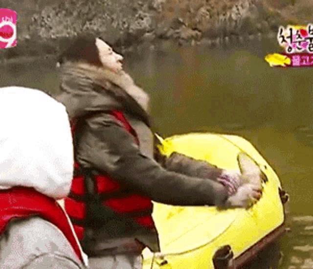 a woman in a life vest is sitting on a yellow raft in the water