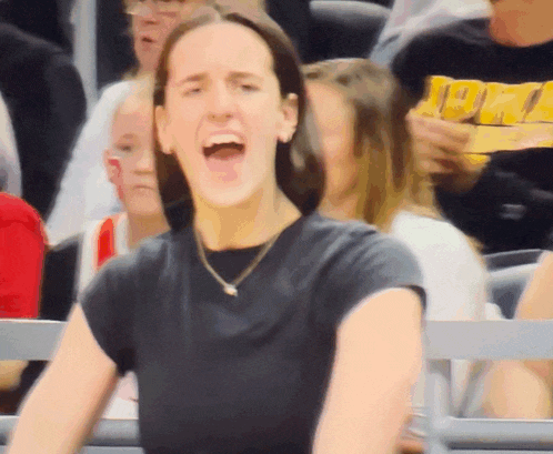 a woman in a black shirt is screaming in a crowd of people