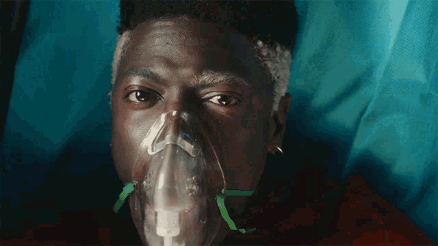 a man with an oxygen mask on his face looks at the camera